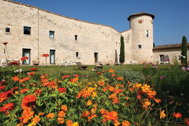 Exterior of hotel, showing a large stone building with lawn in front and orange flowers