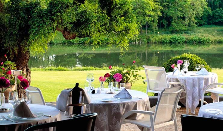 La Reserve Tarn and Lot outdoor restaurant dining area with flowers overlooking a lawn and a river