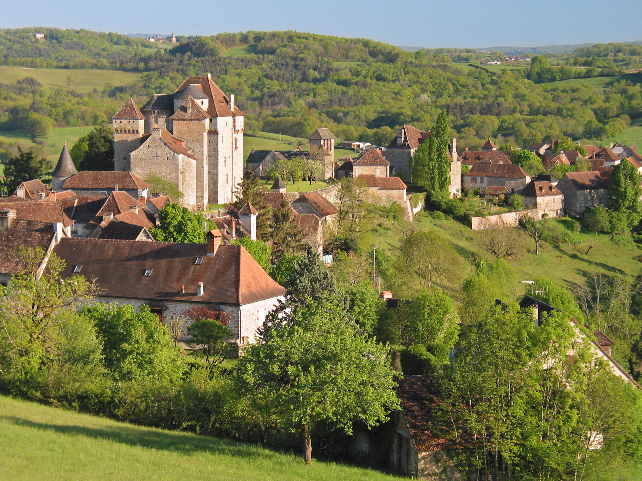 Red tiled roofs and greenery of the village of Curemonte in the Lot valley