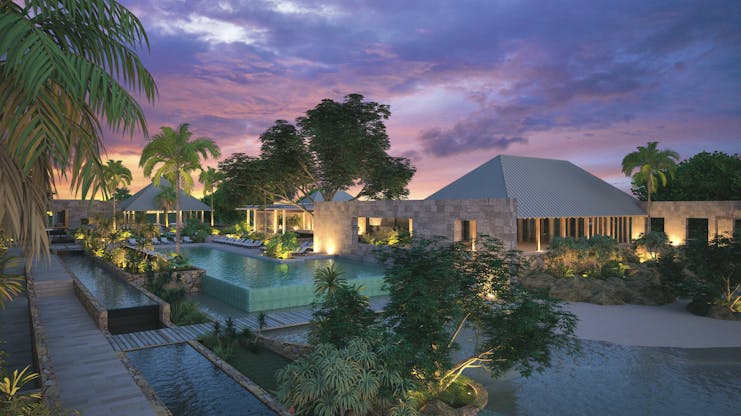 View of exterior of hotel and pool with pink sunset in the sky and hotel in back ground