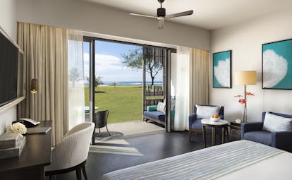 Guestroom with sea view, showing doors opening onto a terrace area with grass and sea in the distance