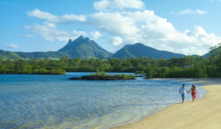 Four Seasons Mauritius beachfront couple walking on the beach wooded mountain