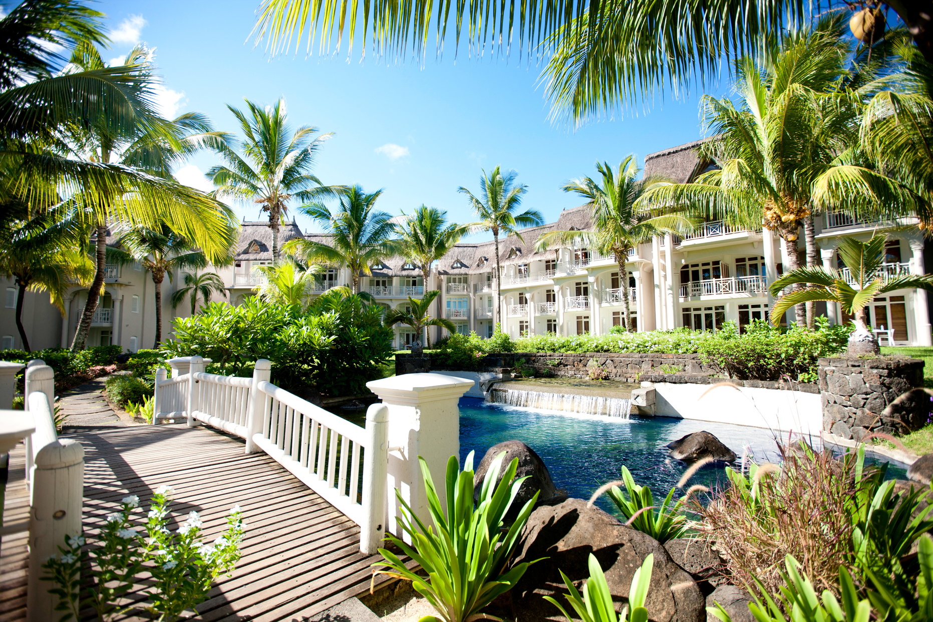Buildings with bridge going over river and buildings with palm trees around hotel exterior