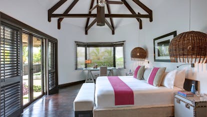 Beach front villa bedroom with large double bed and doors opening up onto beach