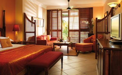 Junior suite with orange and beige colour scheme, large double bed and terrace balcony