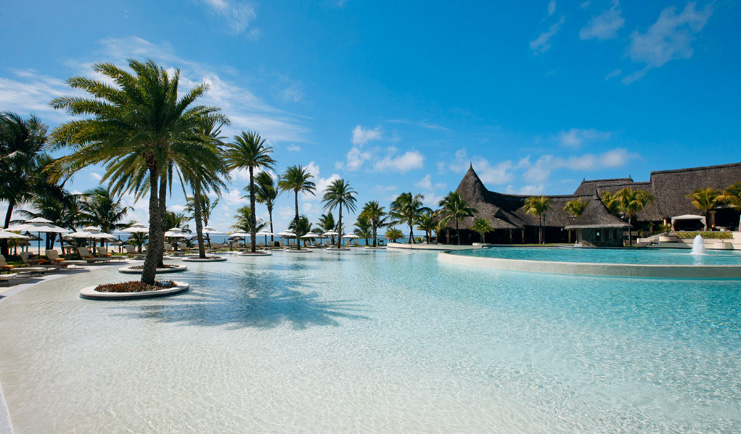 Outdoor pool with sun loungers and palm trees around the outside
