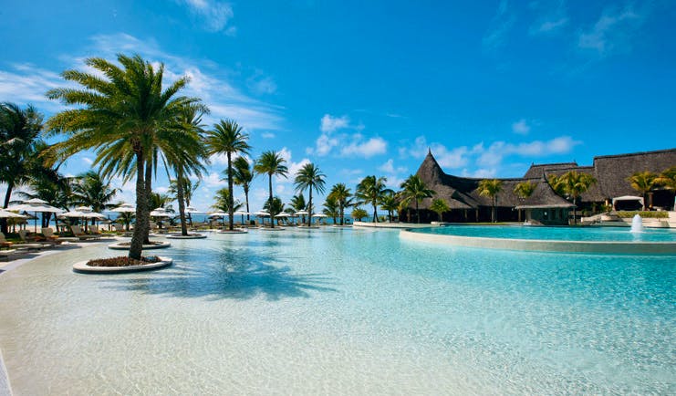 Outdoor pool with sun loungers and palm trees around the outside