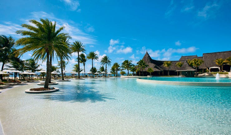 Outdoor pool with sun loungers and palm trees around the outside