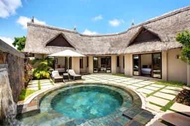 Prestige villa circular plunge pool with beach hut roof villa behind and sun loungers on the terrace