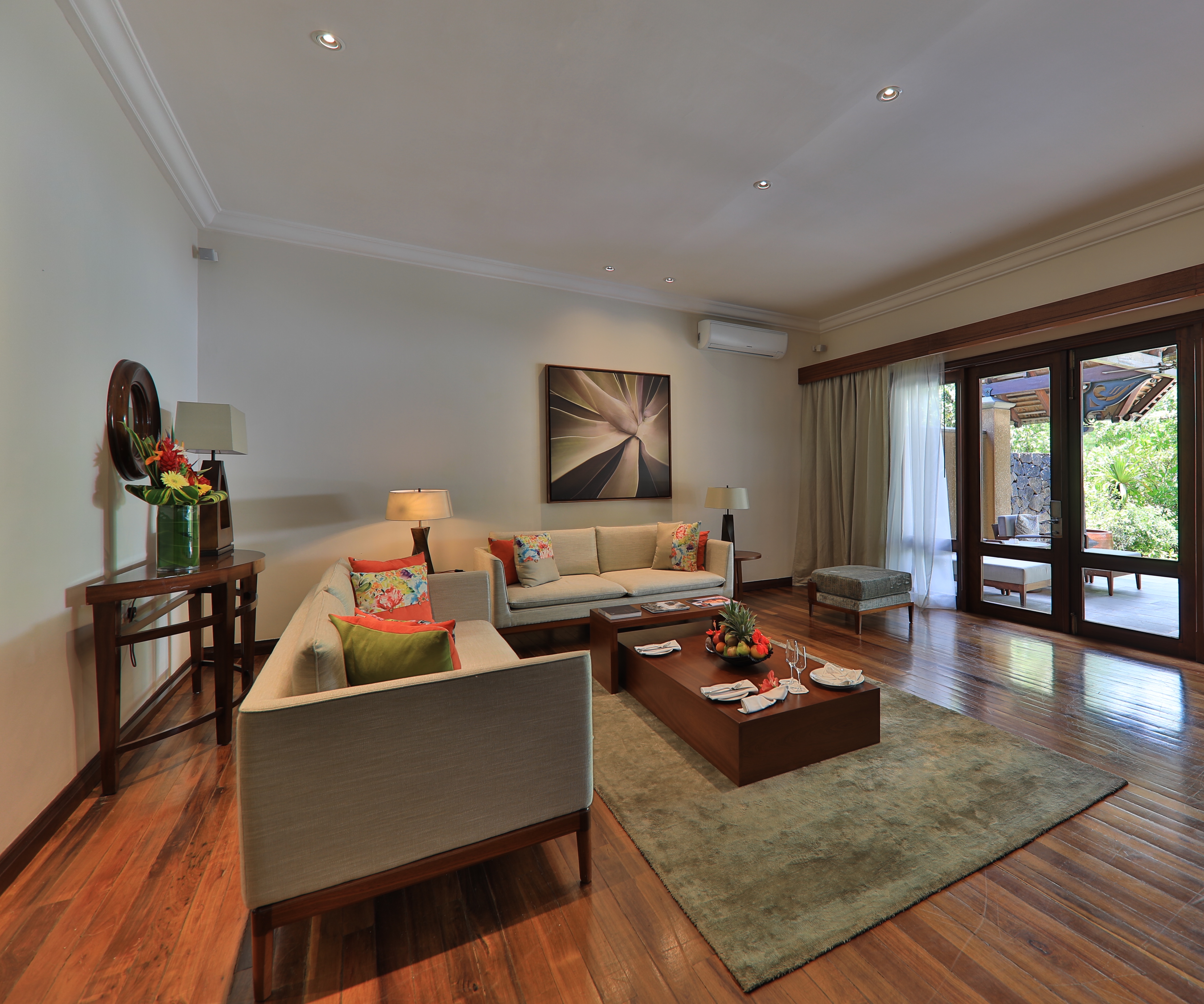 Exclusive suite pool villa living area with large sofas, coffee table and doors opening onto an outdoor terrace area