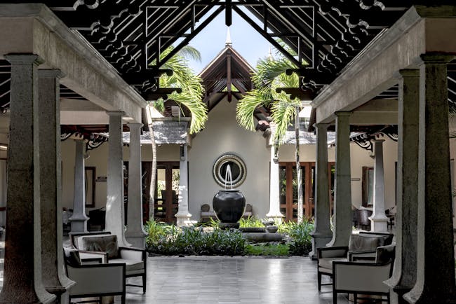 Lobby with seating areas, a water fountain and palm trees