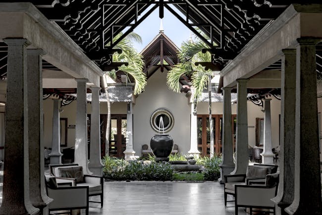 Lobby with seating areas, a water fountain and palm trees