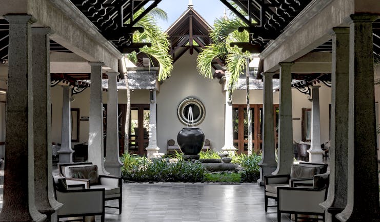 Lobby with seating areas, a water fountain and palm trees