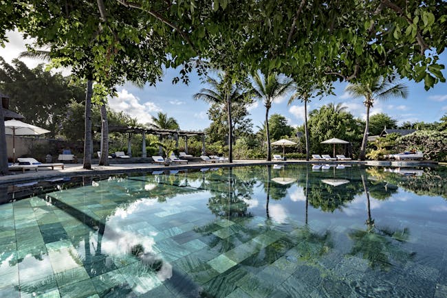 Main pool with sun loungers, umbrellas and palm trees around the outside 