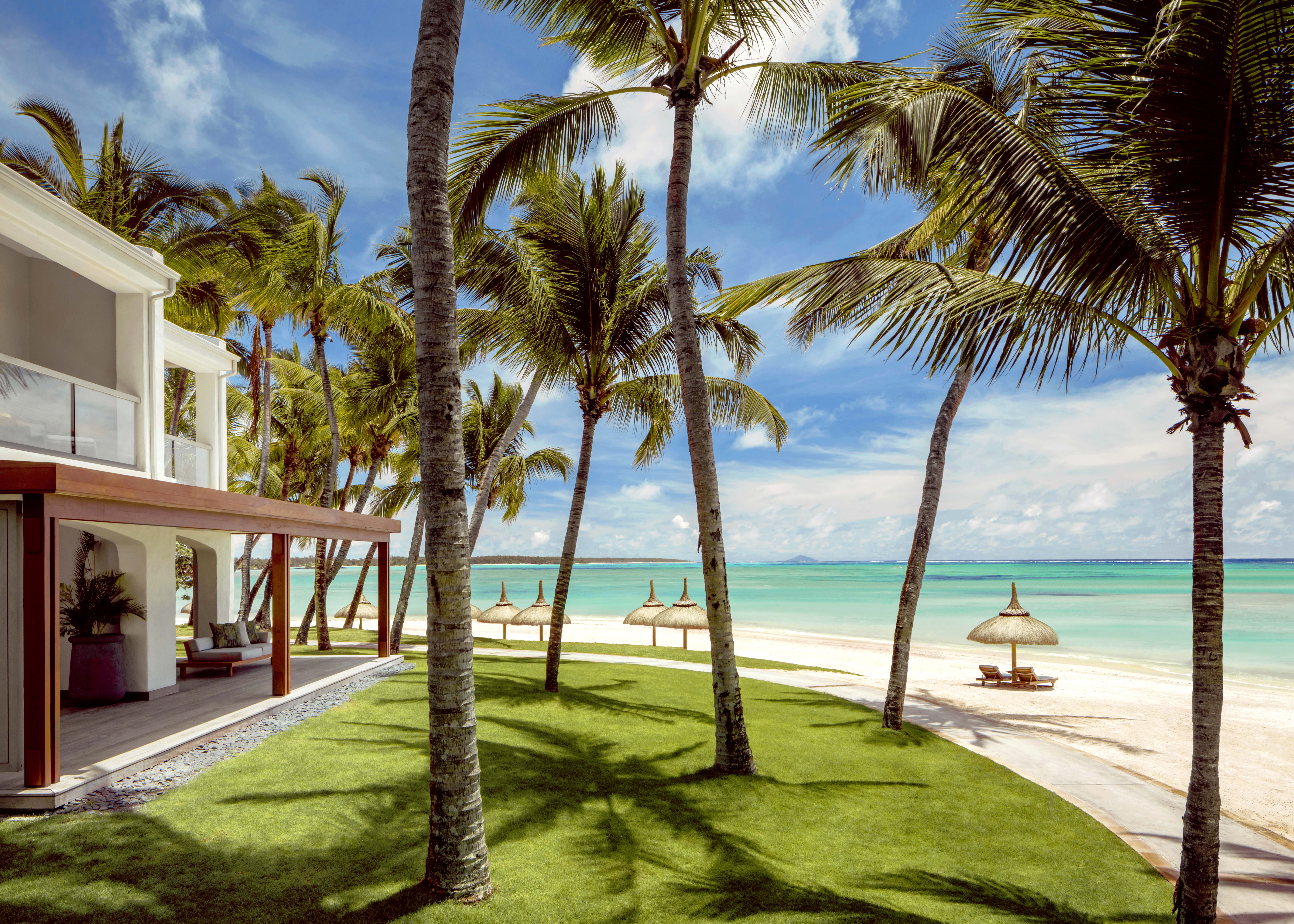 Ocean suite exterior with lawn, palm trees, access to the beach and sea 