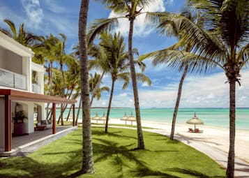 Ocean suite exterior with lawn, palm trees, access to the beach and sea 