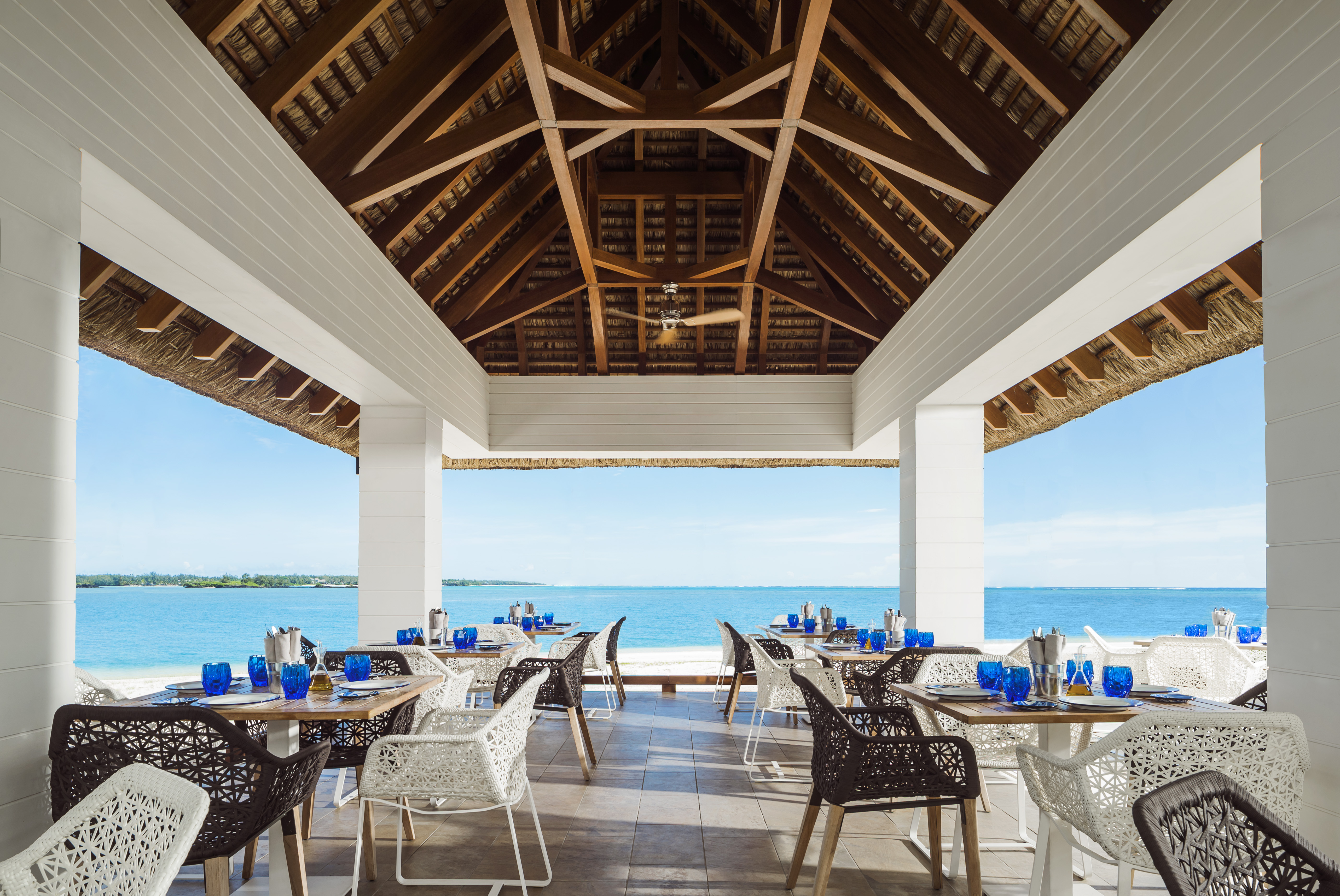 La Pointe restaurant interior with sea in the distance and tables and chairs set up under beach hut style roof