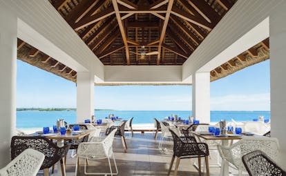 La Pointe restaurant interior with sea in the distance and tables and chairs set up under beach hut style roof