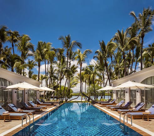 Wellness spa pool with lots of palm trees around and sun loungers and umbrellas