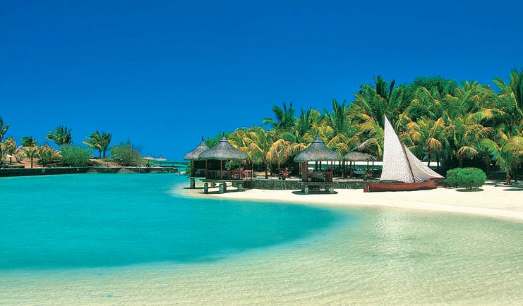 Paradise Cove Mauritius beach front palm forest thatched pavilions boat on sand