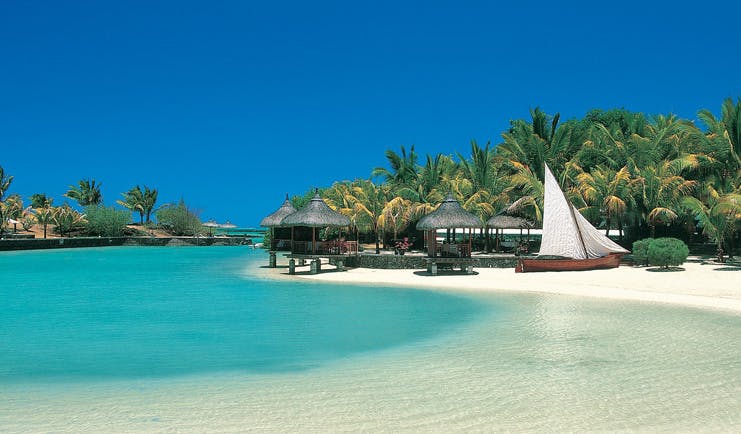 Paradise Cove Mauritius beach front palm forest thatched pavilions boat on sand