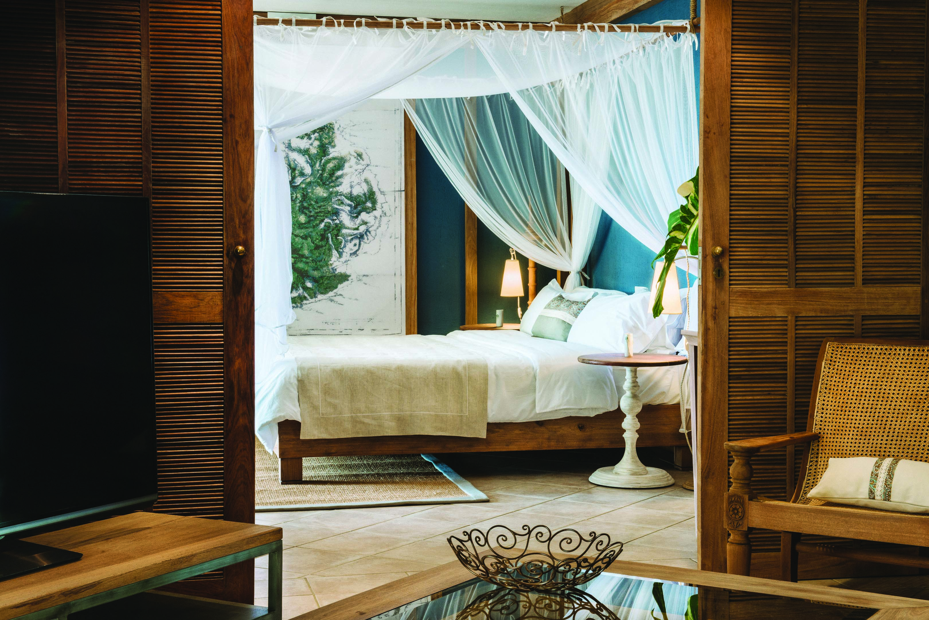 Paradise Cove senior suite, canopied bed, living area with wicker doors, armchairs, television