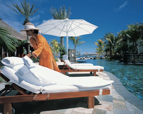 Shangri La Le Touessrok Mauritius poolside woman preparing sun lounger umbrellas palm trees
