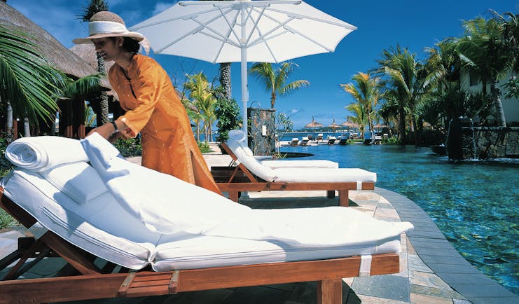 Shangri La Le Touessrok Mauritius poolside woman preparing sun lounger umbrellas palm trees