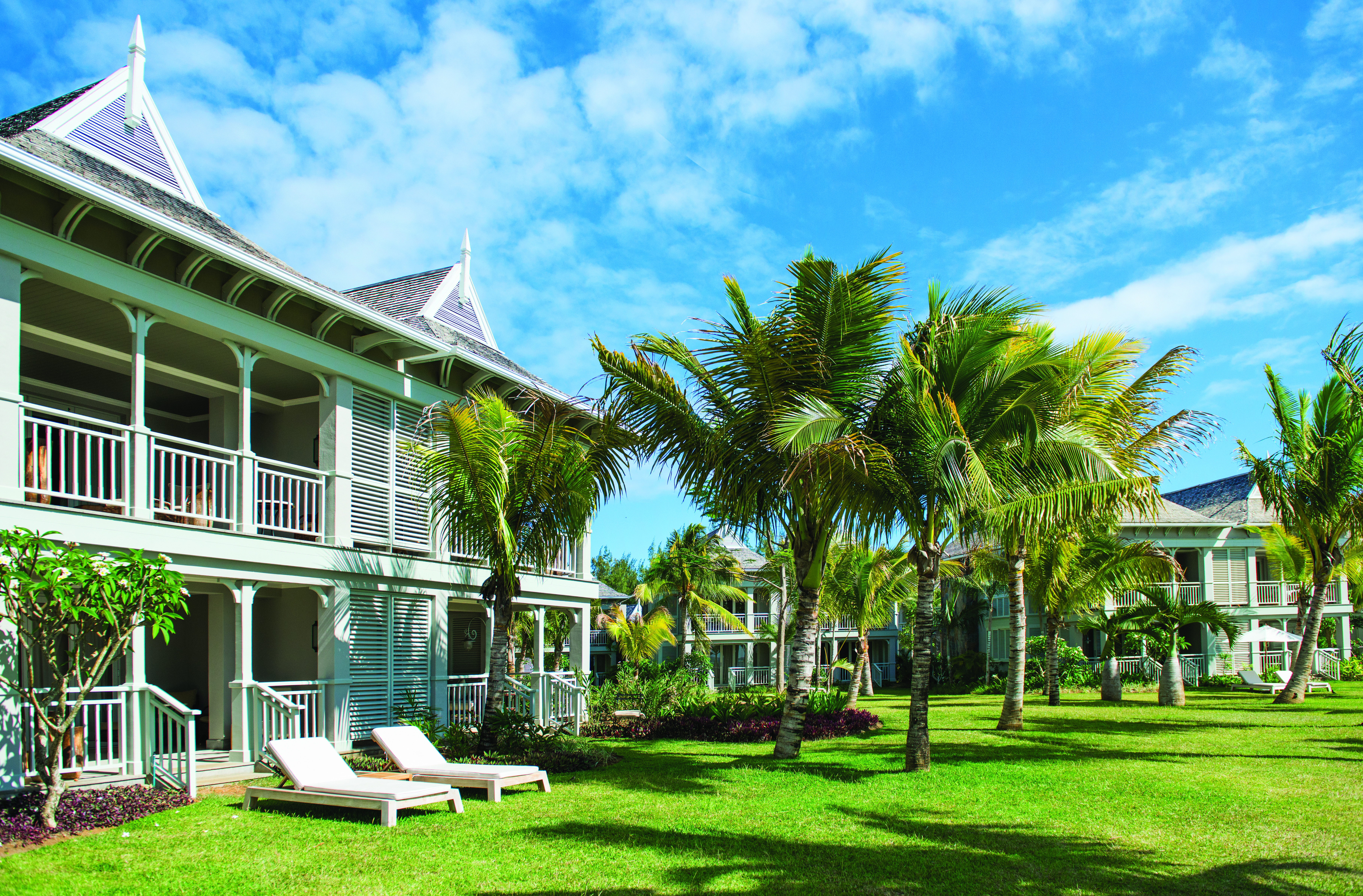 Exterior of hotel and pool showing large stone building, and sun loungers around the pool