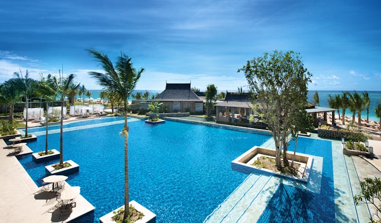 Swimming pool with palm trees built into the floors and views out over the sea