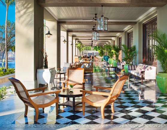 Terrace area with tables and chairs set up outside with a porch overhead