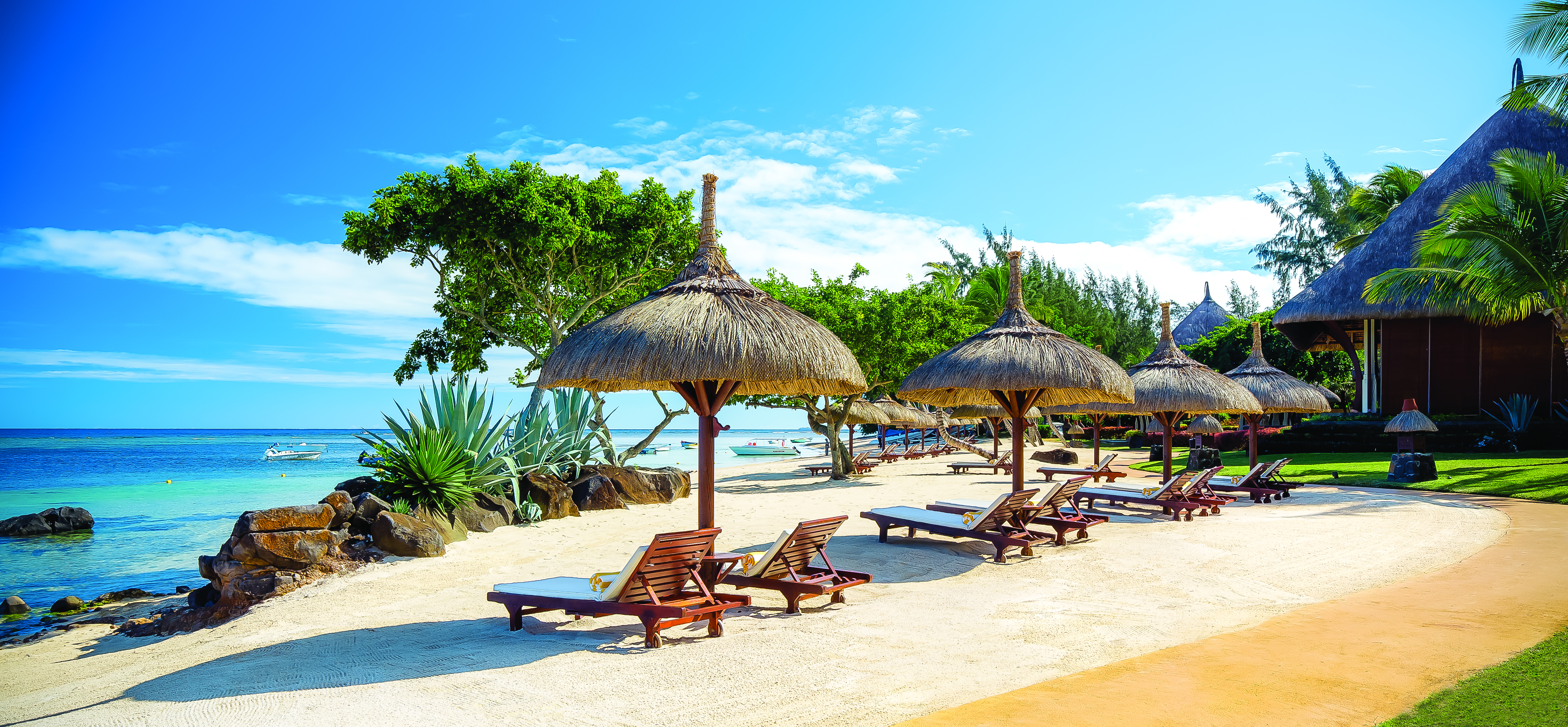 Beach view with sun loungers and beach hut umbrellas near the sea on sand