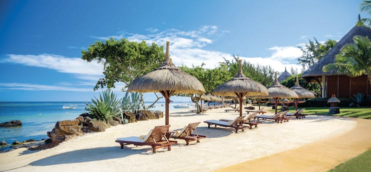 Beach view with sun loungers and beach hut umbrellas near the sea on sand