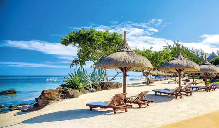 Beach view with sun loungers and beach hut umbrellas near the sea on sand