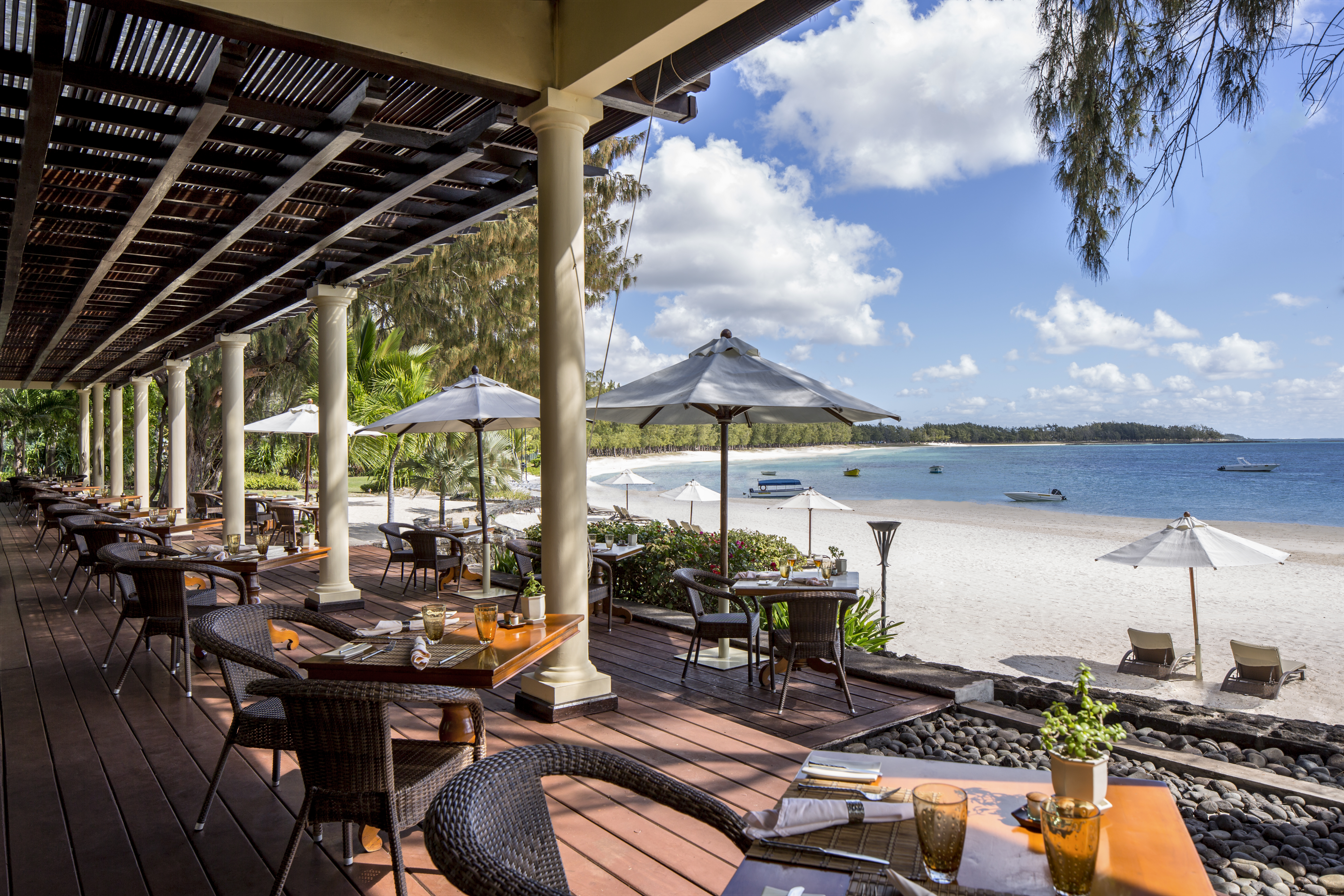 Plantation restaurant with tables set up on wooden decking and looking out over the sea 