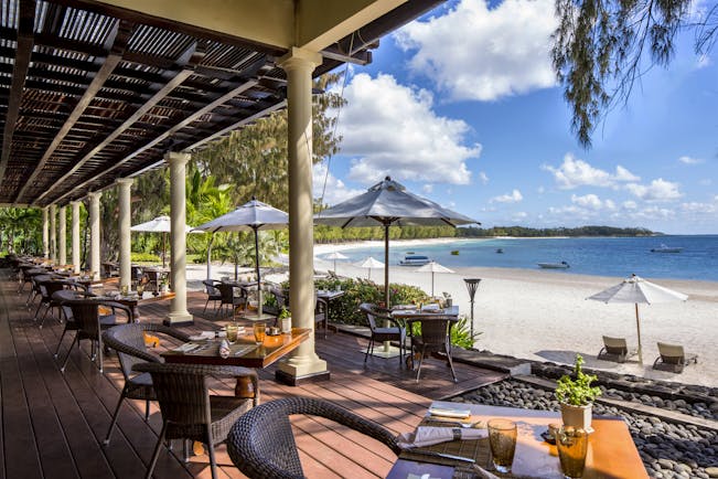 Plantation restaurant with tables set up on wooden decking and looking out over the sea 