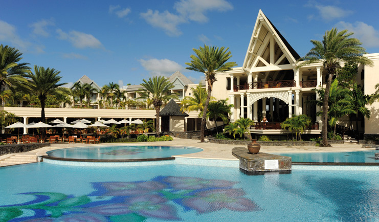 Outside swimming pool with sun loungers, umbrellas and palm trees surrounding it
