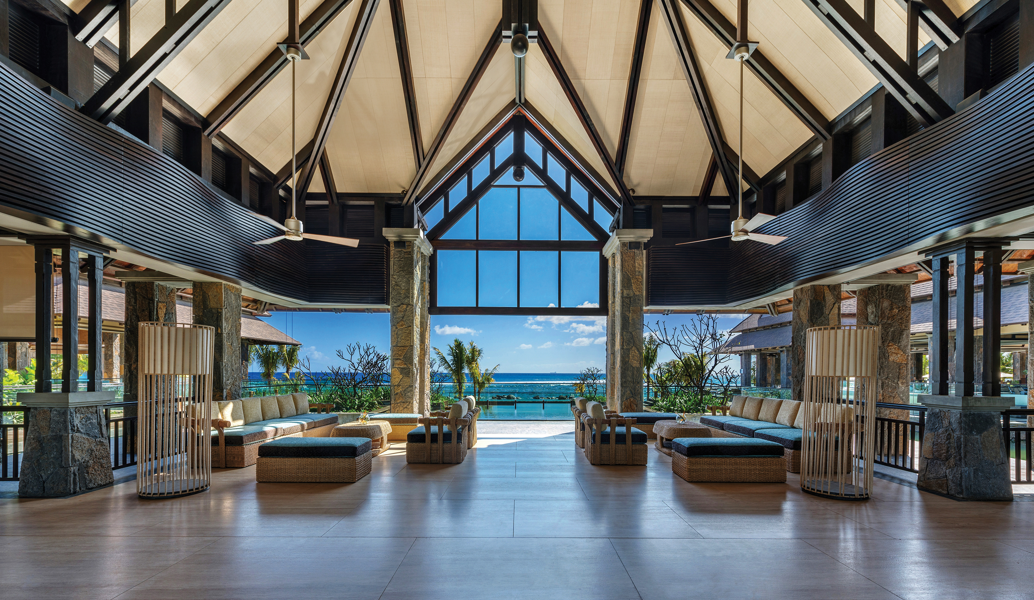 Indoor lobby with high ceilings, seating ares and space opening up over the beach