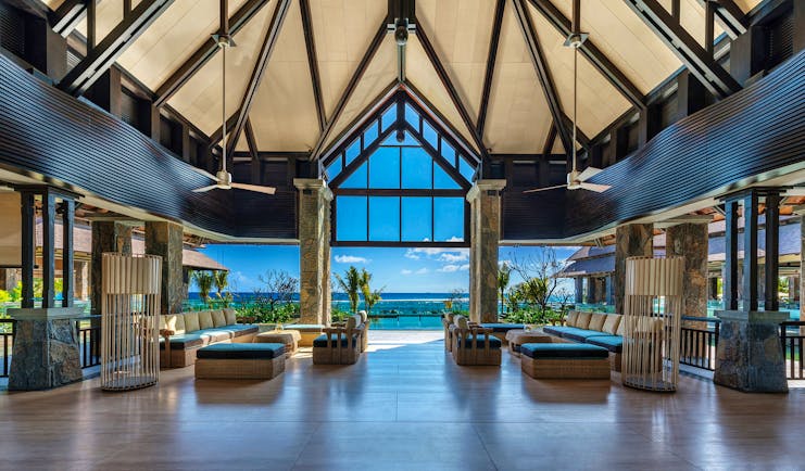 Indoor lobby with high ceilings, seating ares and space opening up over the beach