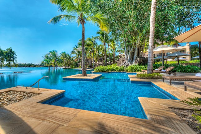 Swimming pool with palm trees round the edges and blue skies