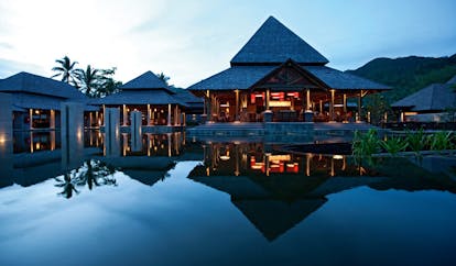 Constance Ephelia Resort Seychelles main building night time pointed rooves outdoor pool