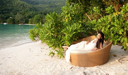 Constance Ephelia Resort Seychelles north beach woman on wicker chair greenery white sand ocean