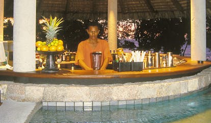 Constance Lemuria Seychelles swim up bar man mixing drinks sunset