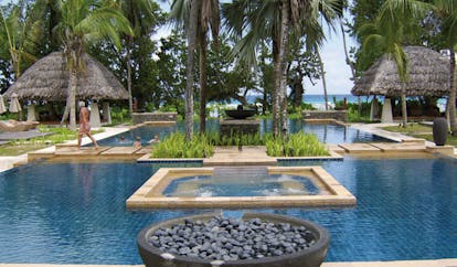 Hilton Labriz Seychelles outdoor swimming pool thatched pavilions palm trees ocean view