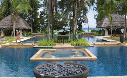 Hilton Labriz Seychelles outdoor swimming pool thatched pavilions palm trees ocean view