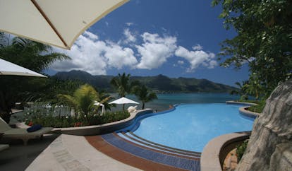 Hilton Northolme Seychelles outdoor pool umbrellas greenery ocean view