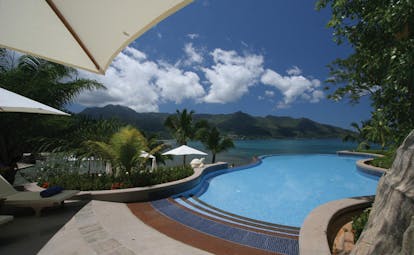 Hilton Northolme Seychelles outdoor pool umbrellas greenery ocean view