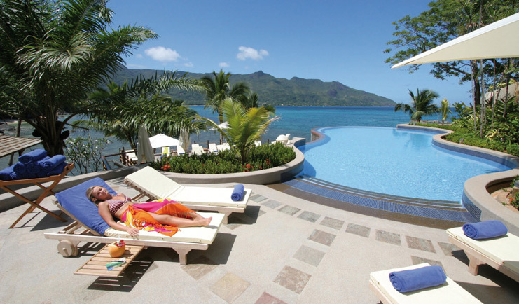 Hilton Northolme Seychelles poolside woman laying on lounger next to outdoor pool sea view