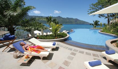 Hilton Northolme Seychelles poolside woman laying on lounger next to outdoor pool sea view