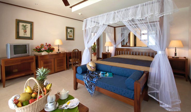 Domaine de la Reserve Seychelles bedroom four poster bed white drapes tropical fruit basket